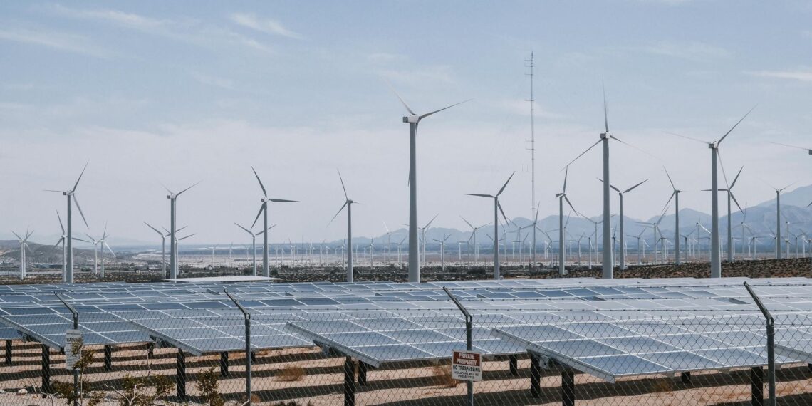 Solar panels and wind turbines installed in a desert landscape, showcasing renewable energy sources in arid conditions.