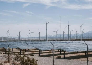 Solar panels and wind turbines installed in a desert landscape, showcasing renewable energy sources in arid conditions.