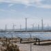 Solar panels and wind turbines installed in a desert landscape, showcasing renewable energy sources in arid conditions.